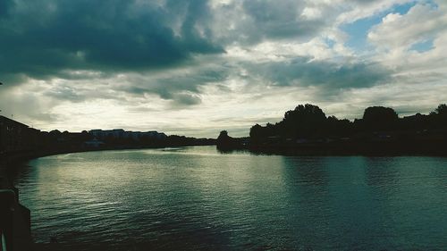 Scenic view of river against cloudy sky