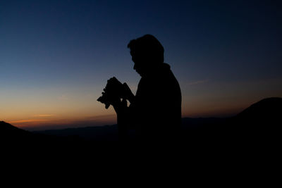 Silhouette man photographing at sunset