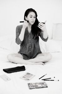 Portrait of young woman using phone while sitting on table