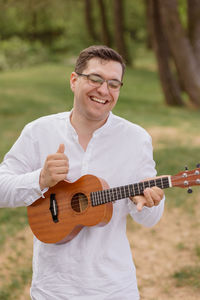 European man walks on the beach and smiles, plays the ukulele and rests on a trip