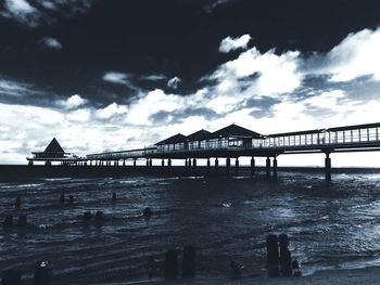 Bridge over river against cloudy sky