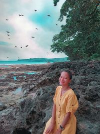 Woman standing at beach against sky