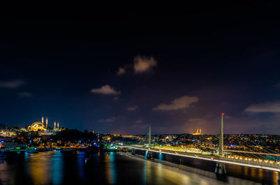 Illuminated bridge over river against sky at night