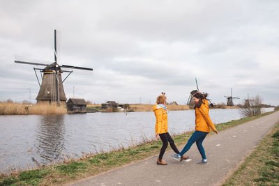 Two girls jumping agains traditional windmill