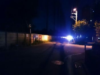 Illuminated street against sky at night