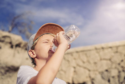 Portrait of boy holding ice cream against sky