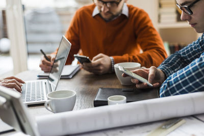 Colleagues at desk with smartphones, laptop and plan