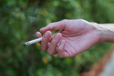 Close-up of hand holding cigarette