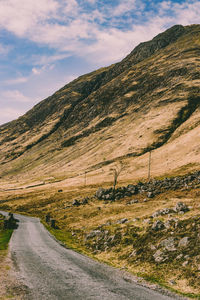 Scenic view of road by mountains against sky