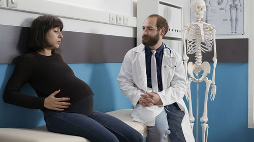 Pregnant woman sitting by doctor in hospital