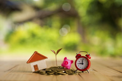 Coins with alarm clock and model home on table