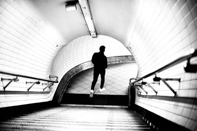 Rear view of man walking on steps in tunnel at subway station