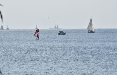 Sailboats sailing in sea against clear sky