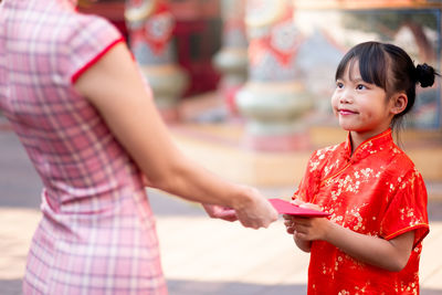 Midsection of woman holding red while standing against blurred background