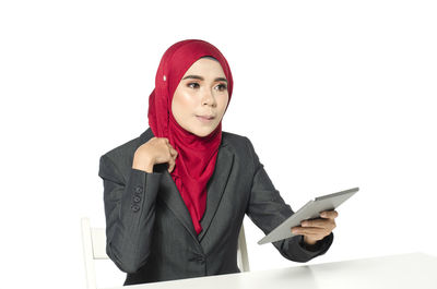 Portrait of young woman standing against white background