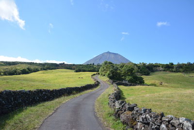 Road leading towards mountains against sky