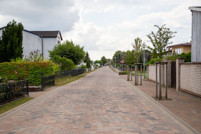 Footpath amidst trees and buildings against sky