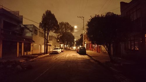 Cars on street in city against sky at sunset