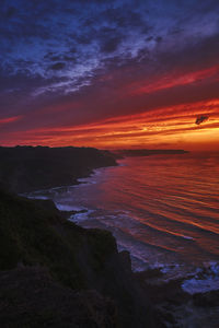 Scenic view of sea against dramatic sky during sunset