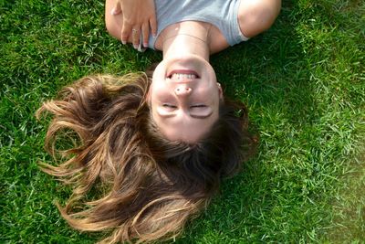 Directly above shot of young woman smiling while lying on grassy field