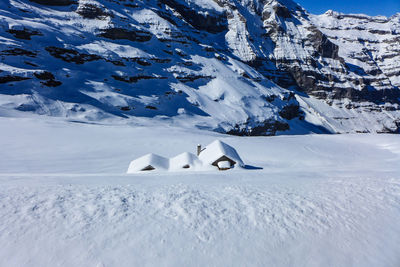 Snow covered landscape against snowcapped mountain