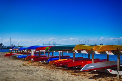 Boats moored on beach against clear blue sky