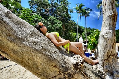 Side view of shirtless man relaxing on rock