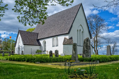 Church and cemetery grassy field against cloudy sky