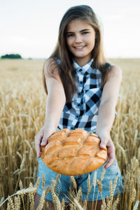 Portrait of smiling young woman holding ice cream on field