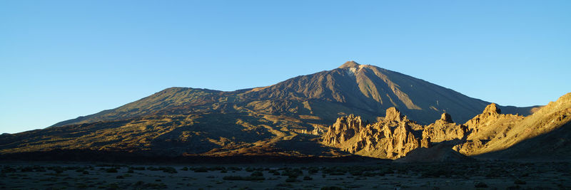 Scenic view of volcanic mountain against clear blue sky