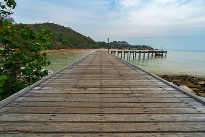 Footpath leading towards sea against sky