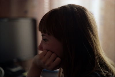 Close-up of thoughtful young woman with hand on chin at home