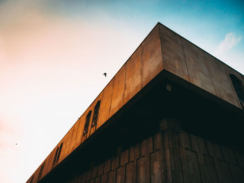 Low angle view of bird on building against sky