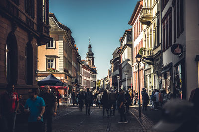 People walking on road amidst buildings in city