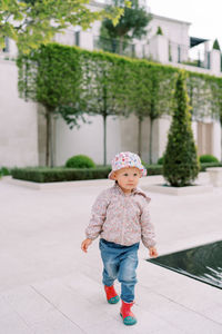 Portrait of boy standing on footpath