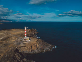 Lighthouse by sea against sky