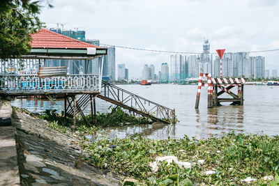 Bridge over river by buildings against sky