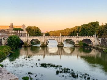 Arch bridge over river tiber against sky during sunset