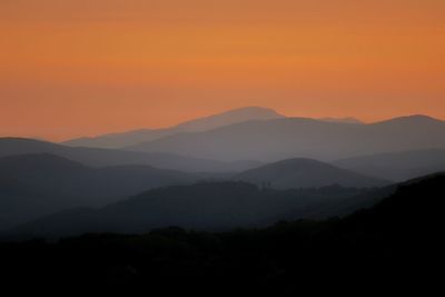 Scenic view of silhouette mountains against romantic sky at sunset