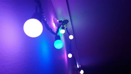 Low angle view of illuminated lighting equipment hanging at night