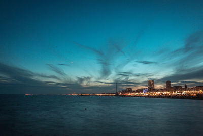 City at waterfront against cloudy sky