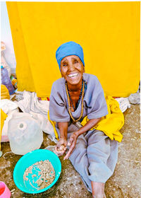 High angle view of old woman mother sitting and heart touching kindness smile against yellow wall