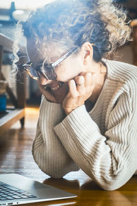 Young woman using mobile phone while sitting on table