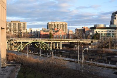 Bridge over river amidst buildings in city against sky