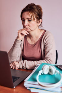 Portrait of young woman using phone while sitting on table