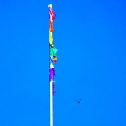 Low angle view of flags against clear blue sky