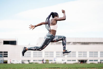 Low section of person jumping against the sky