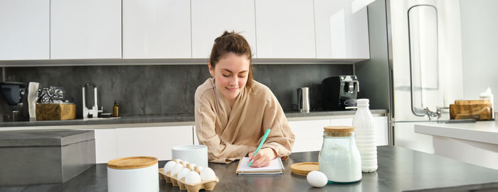 Side view of young woman sitting in kitchen