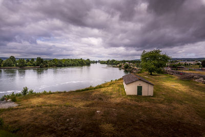 House by lake and buildings against sky