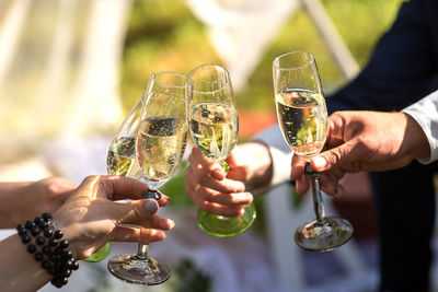 Cropped hands of friends toasting champagne flutes in party